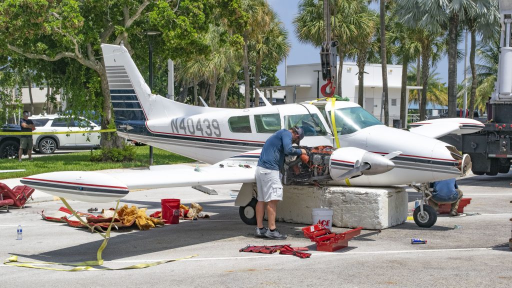 A Piper Twin Comanche PA-39 (PA-30 variant) at a boat ramp in Boca Raton, FL, being prepared to be removed by a crane after landing in the ocean, Aug. 23, 2026. (Photo: Boca Daily News)