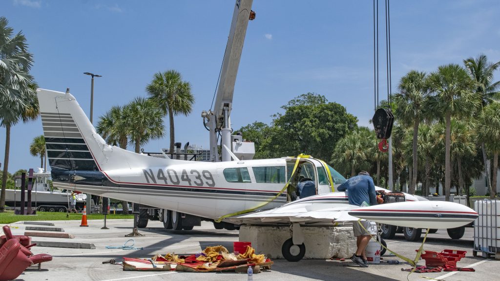 A Piper Twin Comanche PA-39 (PA-30 variant) at a boat ramp in Boca Raton, FL, being prepared to be removed by a crane after landing in the ocean, Aug. 23, 2026. (Photo: Boca Daily News)